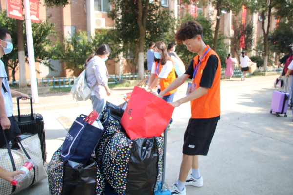 新生辅导员岑雨晨认真地整理新生报到的材料,并贴心地提醒新生做好